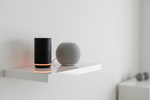 Dois assistentes de voz inteligentes lado a lado numa sala moderna — comparativo Alexa vs Google Home para casa inteligente