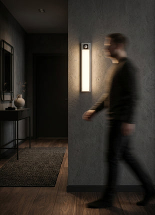 Barra LED com sensor PIR, acesa na parede, perfil estreito e luminoso.