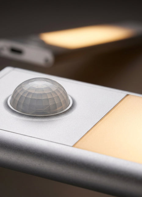Barra LED com sensor PIR: lente circular e faixa de luz amarela.