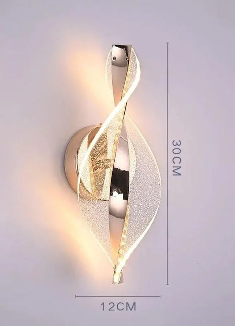 Aplique de parede LED dourado em espiral com luz acesa e medidas 12x30 cm.