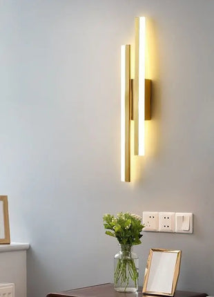 Aplique de parede LED minimalista dourado com barras verticais e luz quente