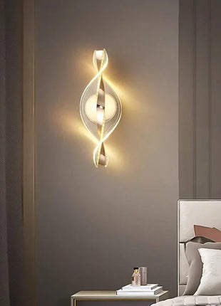 Aplique de parede LED dourado em espiral, com placa circular e luz quente difusa.