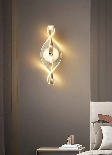 Aplique de parede LED dourado em espiral, com placa circular e luz quente difusa.