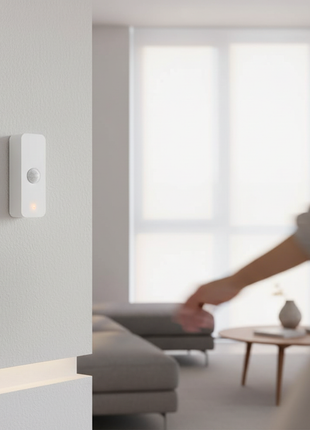 Sensor de movimento PIR branco na parede com luz acesa.