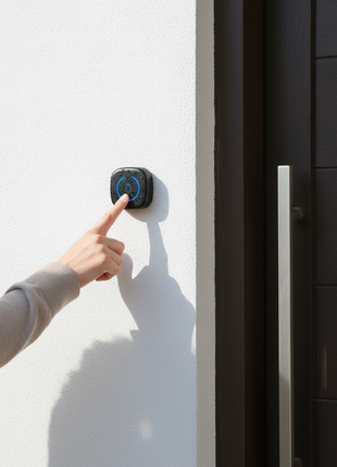 Campainha sem fios Wi‑Fi preta na parede, botão ao alcance da mão.