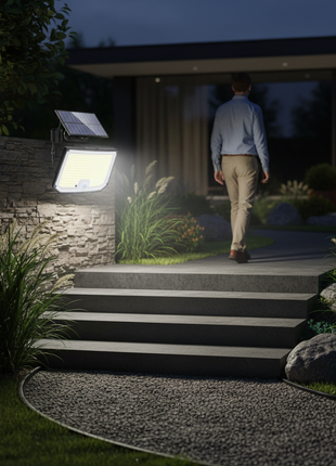 Foco solar LED na parede junto a escadas, luz acesa no jardim à noite